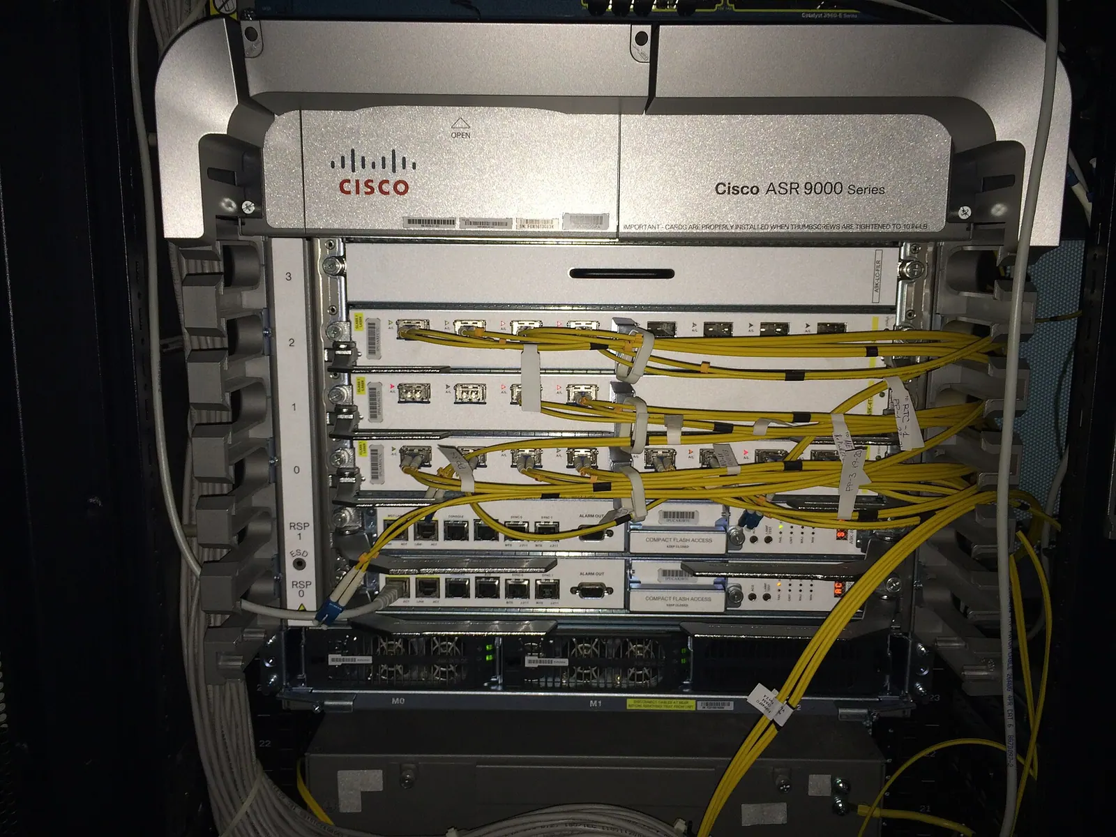 Router lõi Cisco ASR 9000 trong tủ rack với các card đường truyền cắm cáp quang