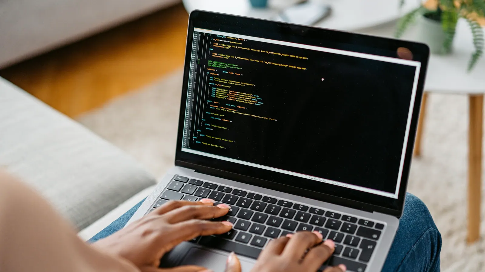Lập trình viên gõ code trên laptop đặt trên đùi