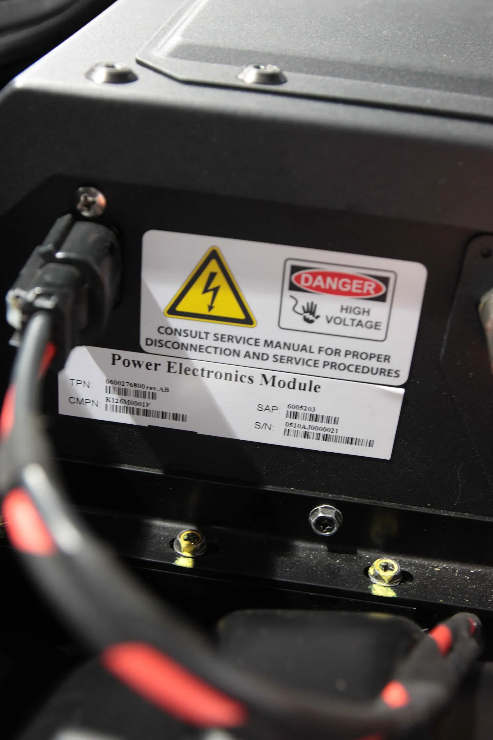 Nhãn cảnh báo điện cao áp màu vàng đỏ trên một module điện tử công suất của xe điện