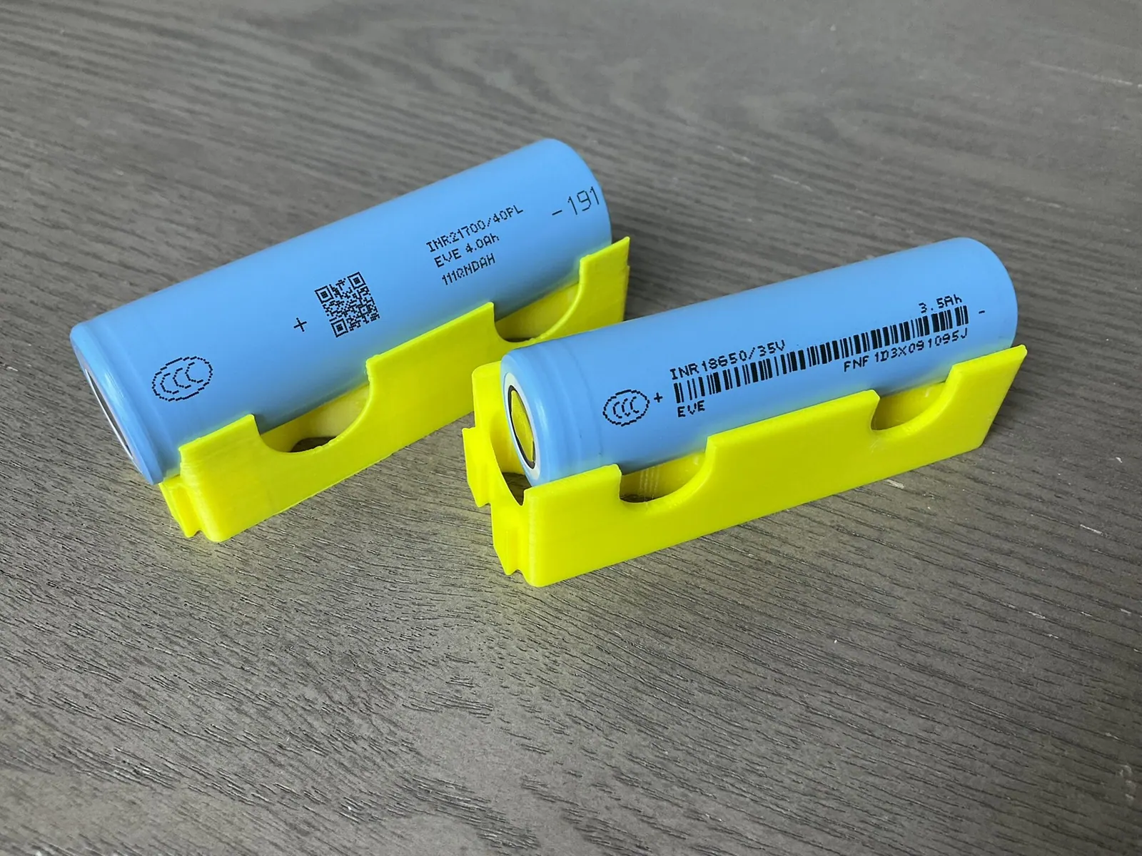 Hai viên cell lithium-ion hình trụ loại 21700 và 18650 đặt trên giá nhựa