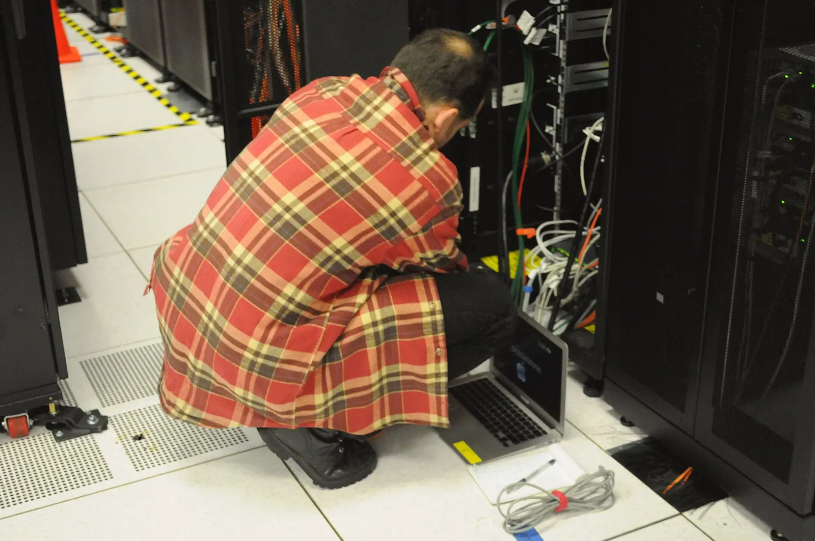 Kỹ thuật viên ngồi cạnh tủ server với laptop, minh hoạ chi phí bảo trì của hệ thống tự viết
