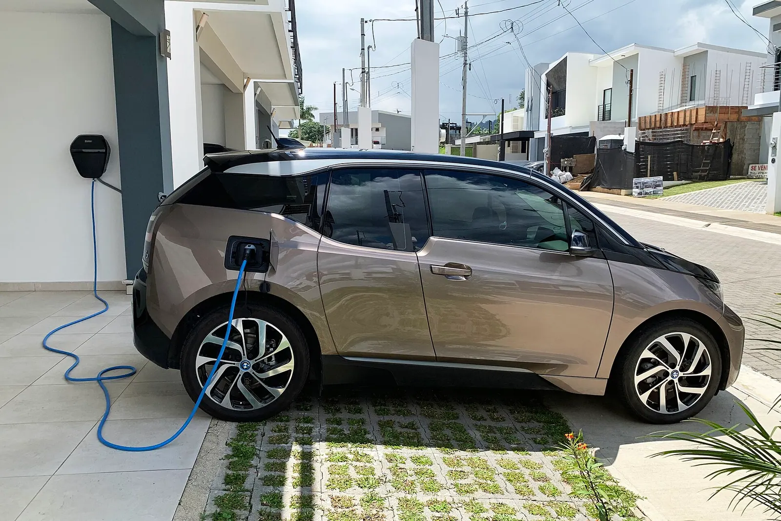BMW i3 đang cắm sạc tại nhà, đỗ trước cửa gara