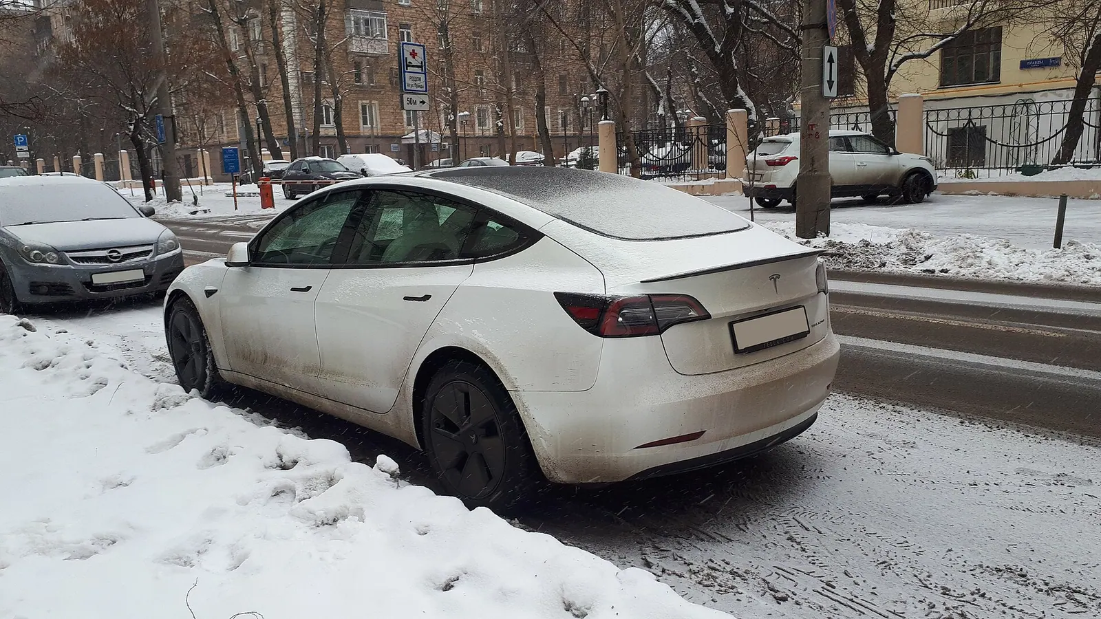 Xe điện Tesla Model 3 màu trắng đỗ bên đường phủ tuyết giữa trời đông