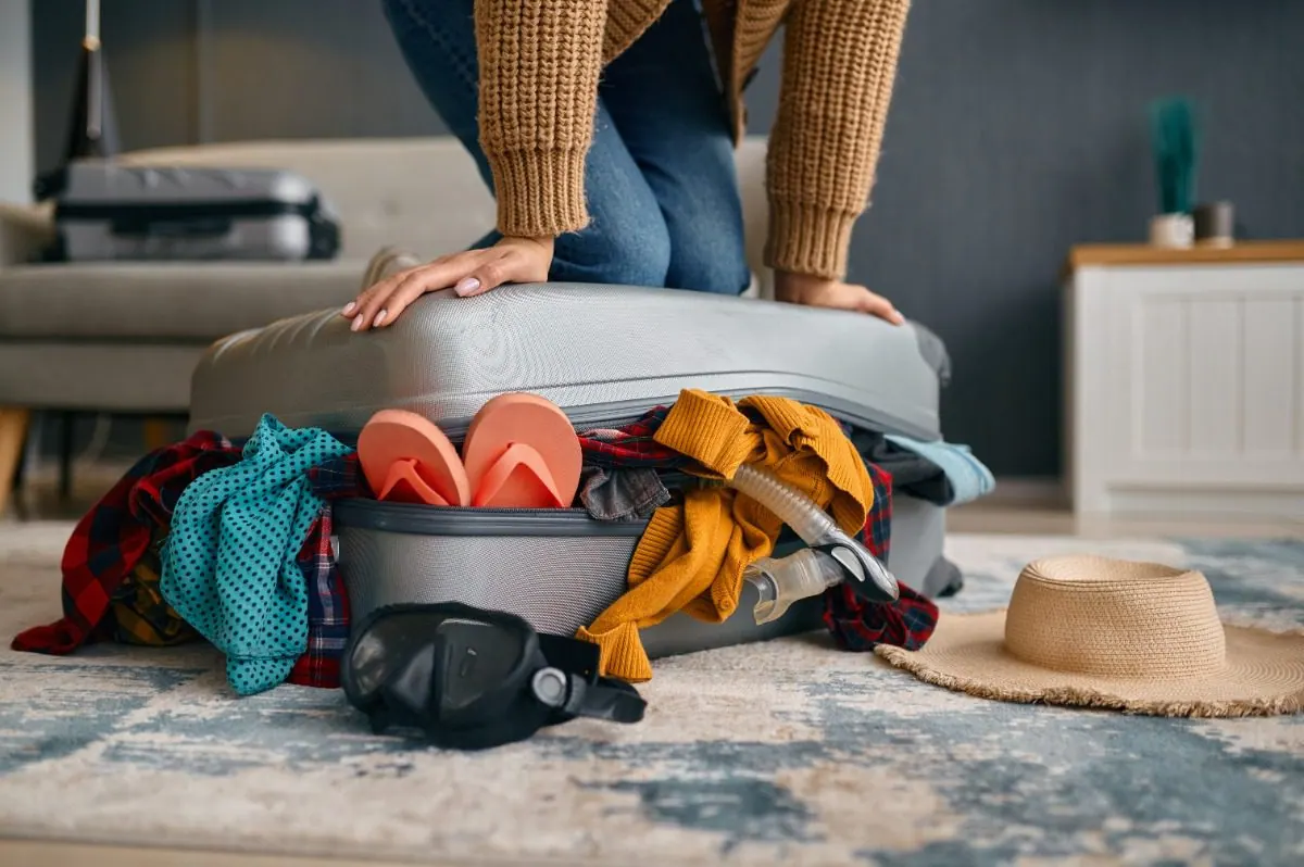 Người phụ nữ cố đè nắp chiếc vali bị nhồi quá nhiều quần áo